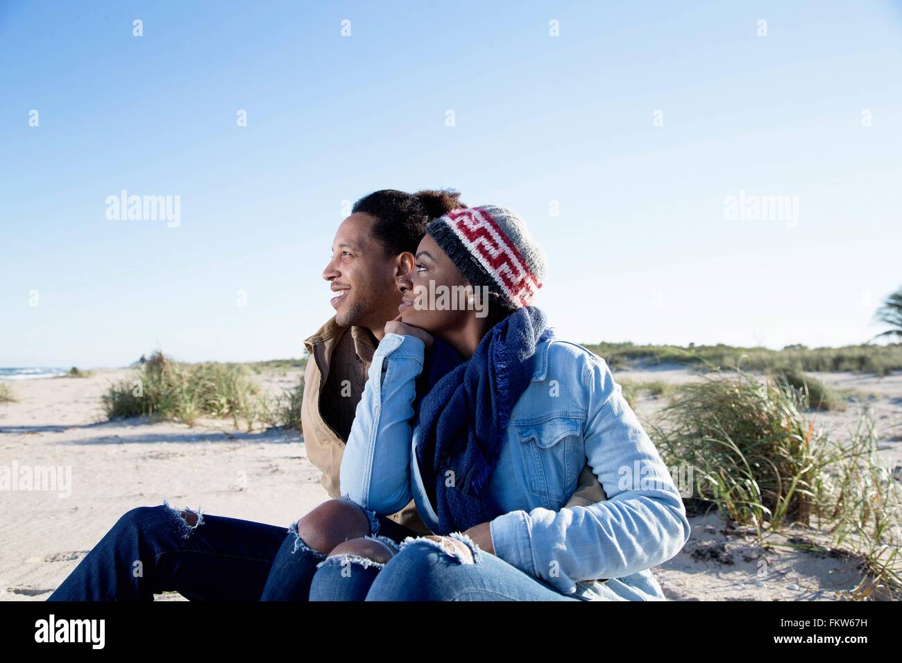 Junges Paar sitzt am Strand, betrachten Stockfoto
