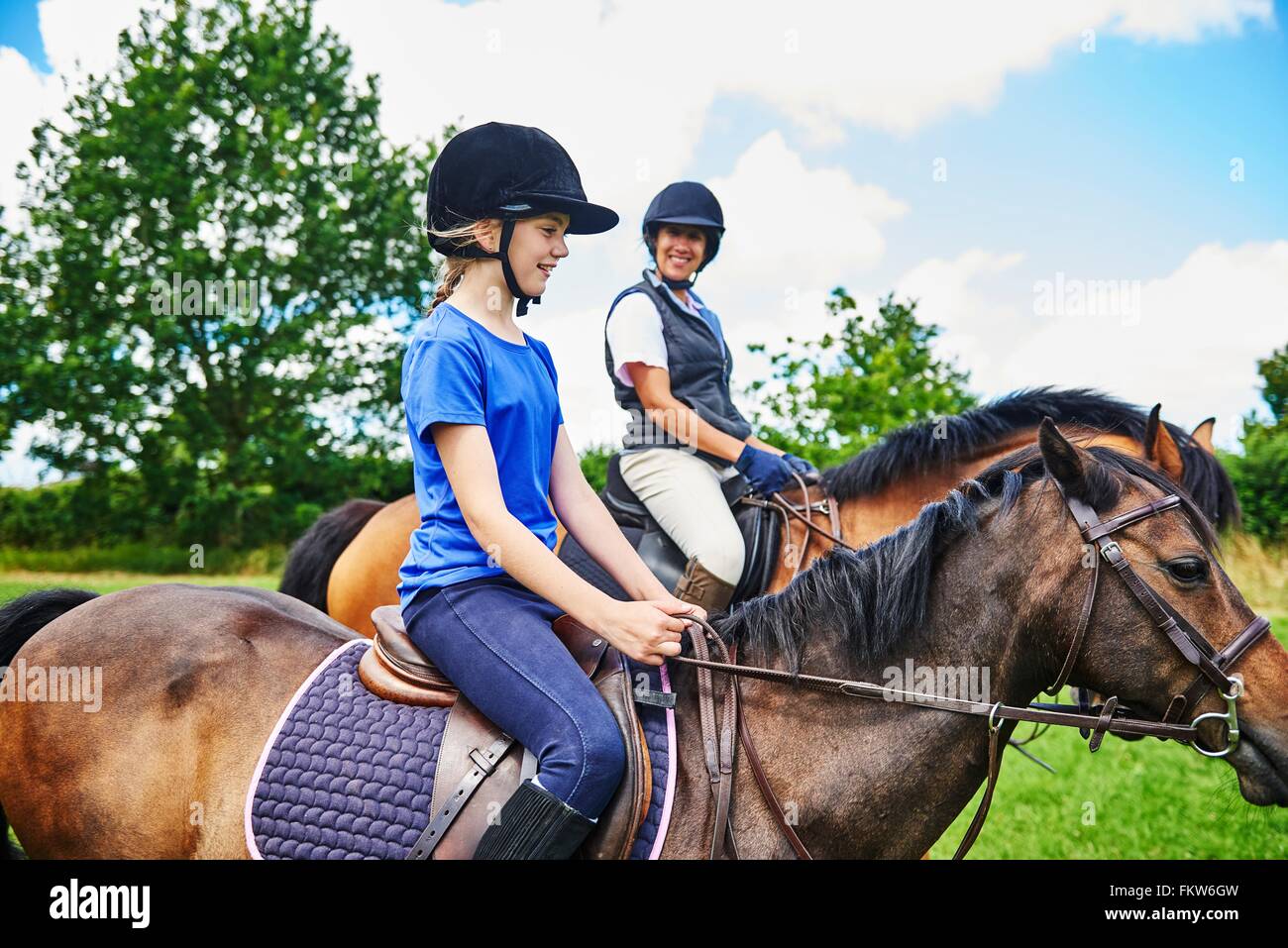 Seitenansicht der Reife Frau und Mädchen auf Pferde tragen Reiten Hüte lächelnd Stockfoto