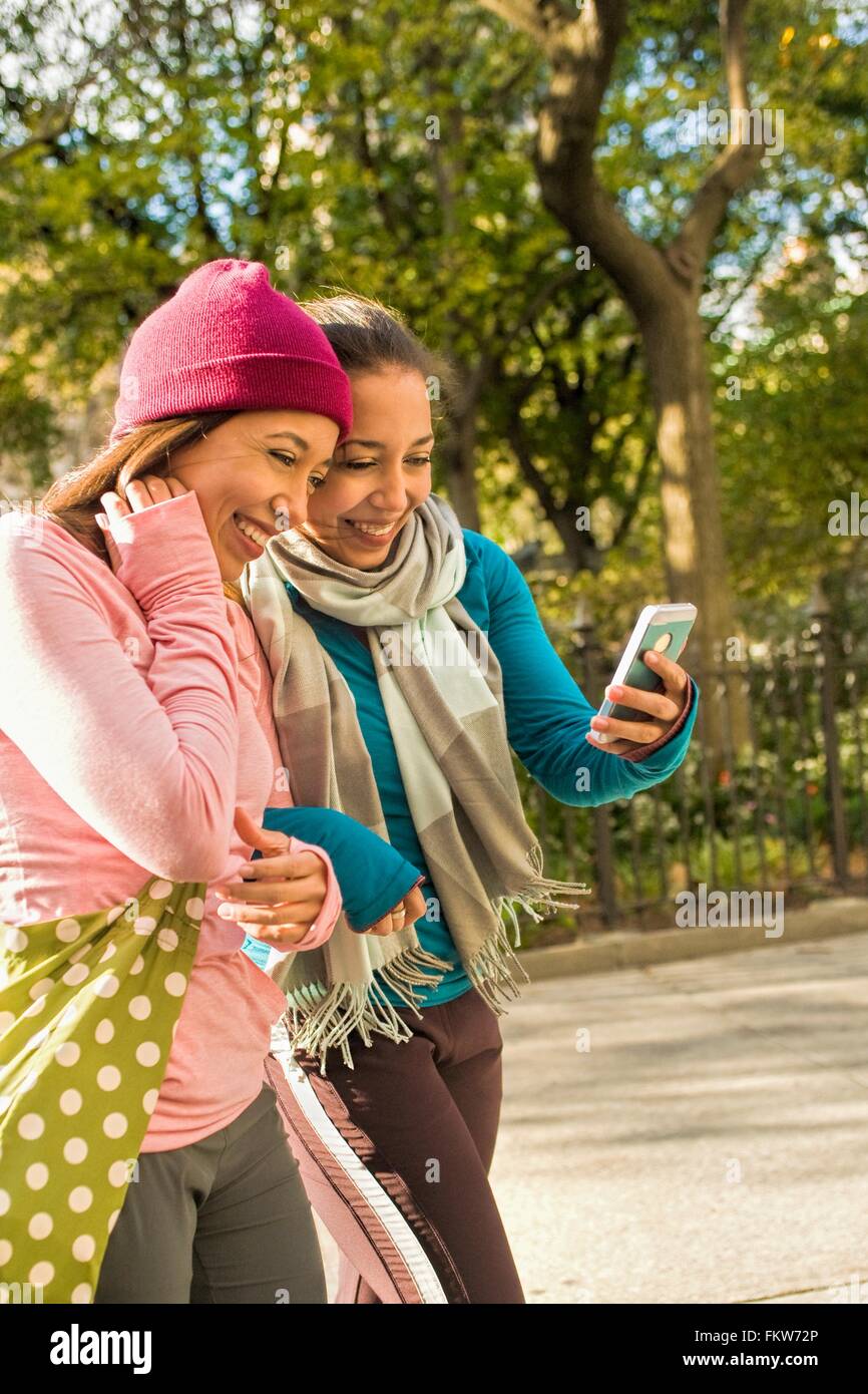 Zwillinge zu Fuß und mit Smartphone in park Stockfoto