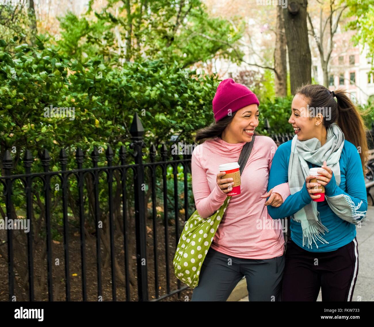Zwillinge, die zu Fuß mit Kaffee im park Stockfoto