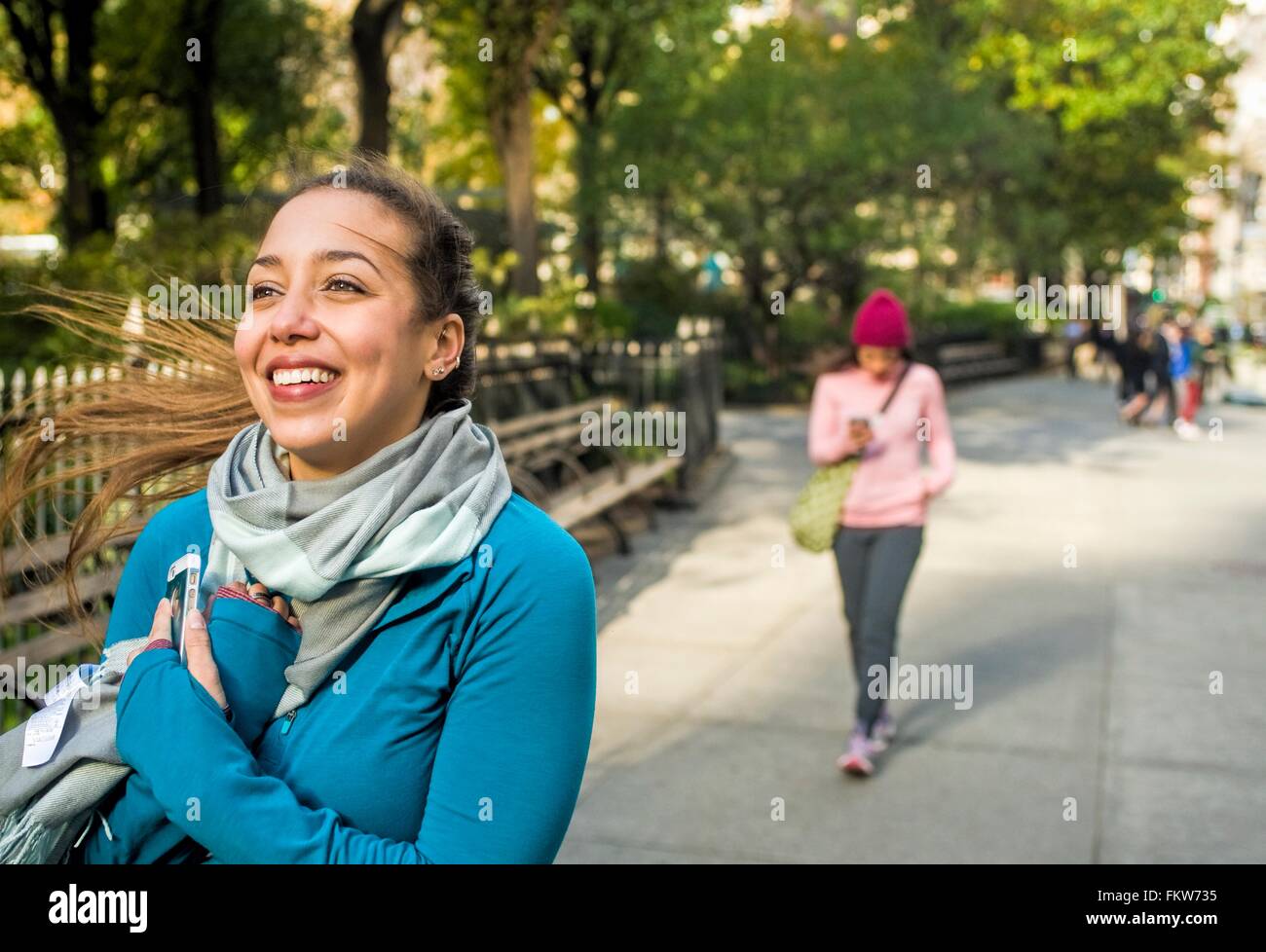 Junge Frau zu Fuß und lächelnd in park Stockfoto
