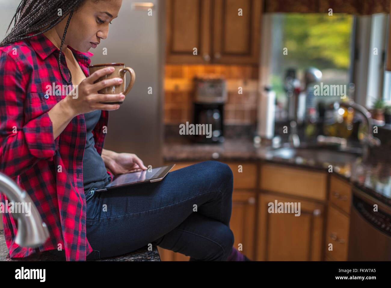 Mitte erwachsenen Frau sitzt in Küche mit digital-Tablette Stockfoto