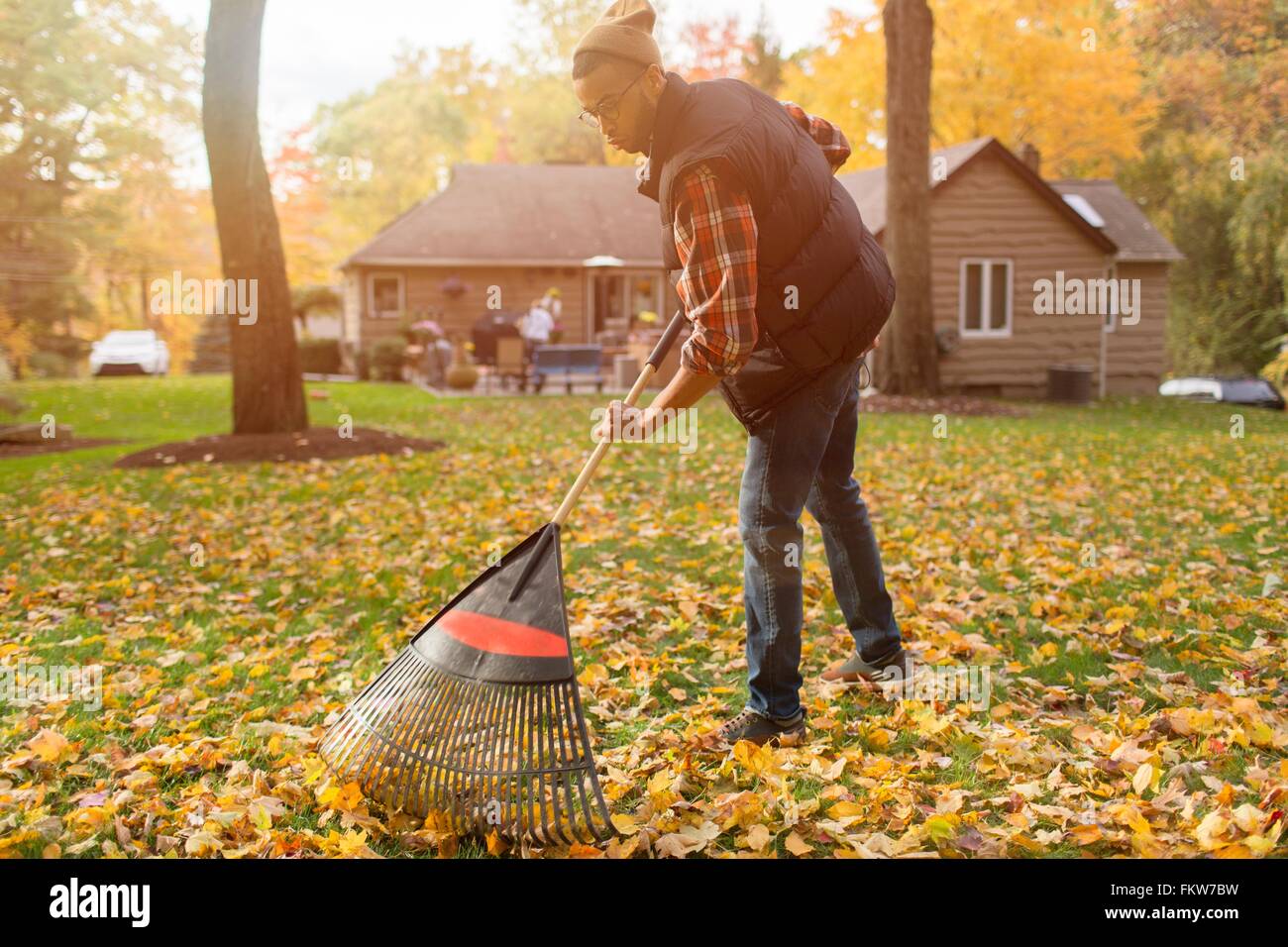 Mitte erwachsener Mann verlässt im Herbst Rechen Garten Stockfoto