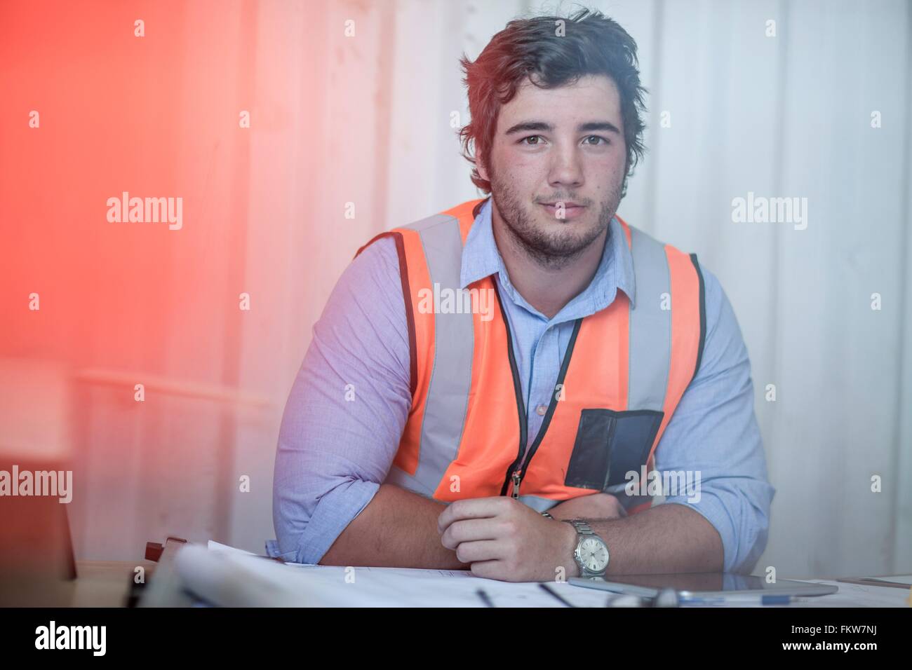 Porträt des jungen männlichen Bauarbeiter sitzen am Schreibtisch in tragbaren Kabine Stockfoto