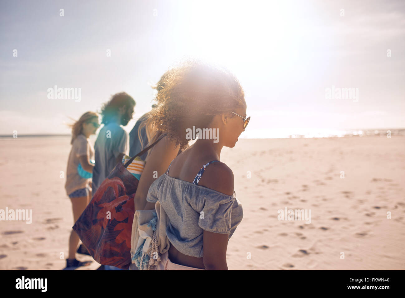 Aufnahme einer Gruppe von jungen Freunden an einem sonnigen Tag am Strand entlang spazieren. Männer und Frauen, die Sommer-Urlaub am Strand. Stockfoto