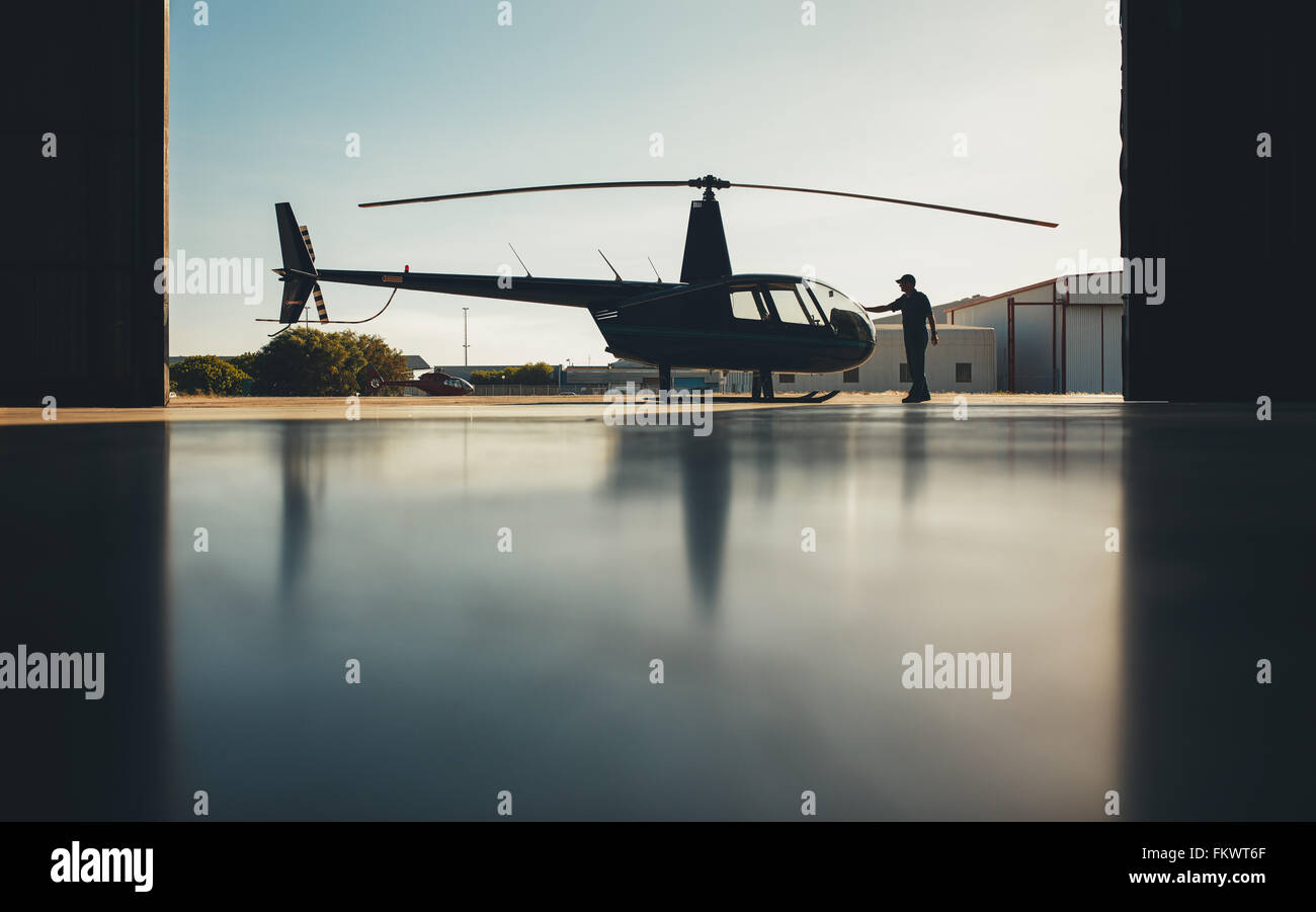 Silhouette der Hubschrauber im Hangar mit einem Piloten. Pilot preflight-Überprüfung eines Hubschraubers zu tun. Stockfoto