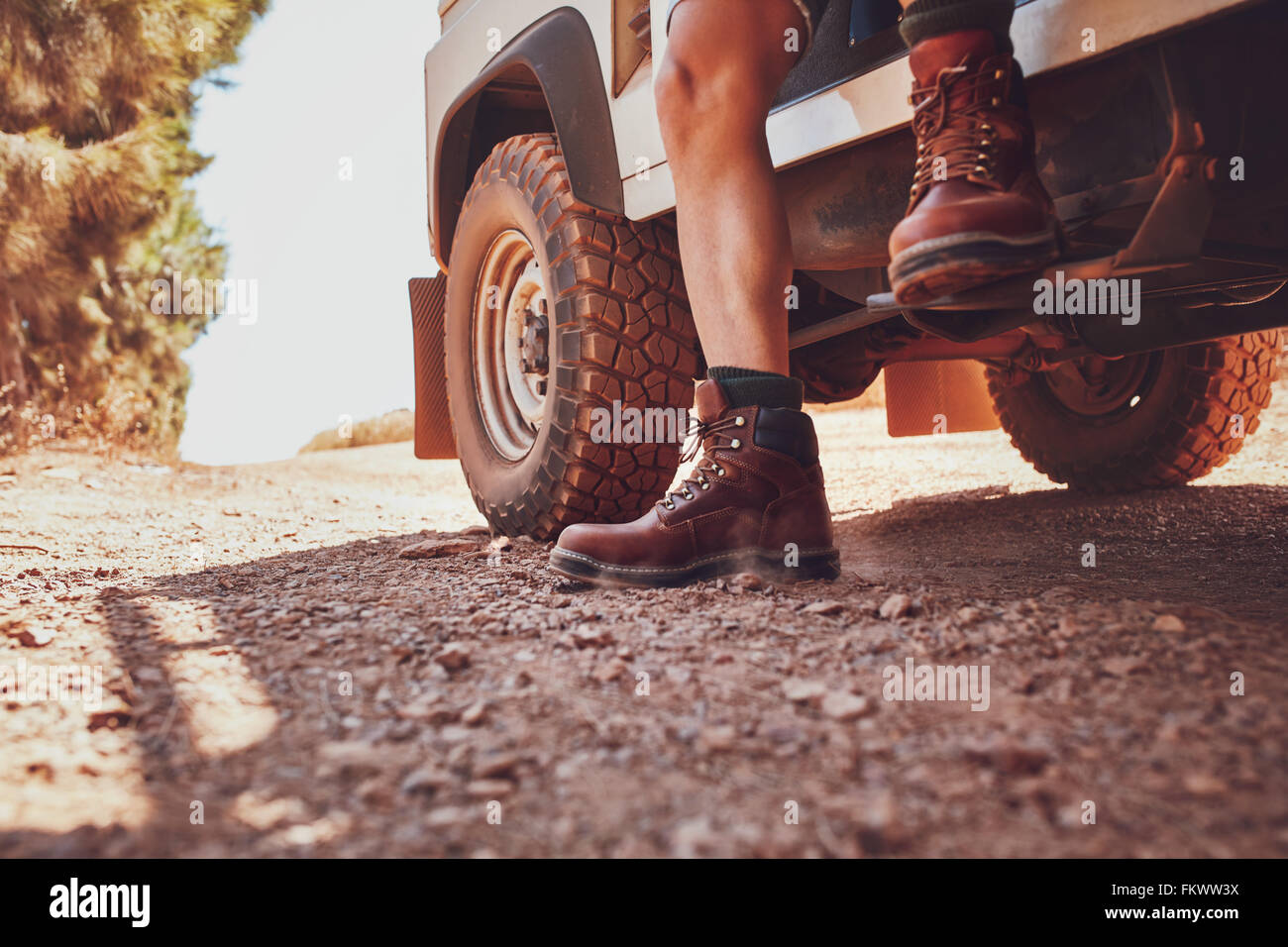 Nahaufnahme von männlichen Bein mit Lederschuh heraustreten aus einer off-Road-Fahrzeug. Auto auf dem Feldweg in Landschaft. Stockfoto