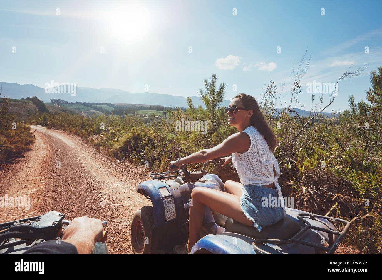 Junge Frau auf Quad-Bike auf einem Pfad. Junge Autofahrerin all-Terrain-Fahrzeug in der Natur an einem sonnigen Tag. Stockfoto