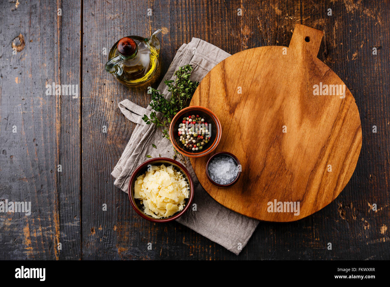 Schneidebrett, Gewürzen und Parmesan-Käse auf dunklem Holz Stockfoto