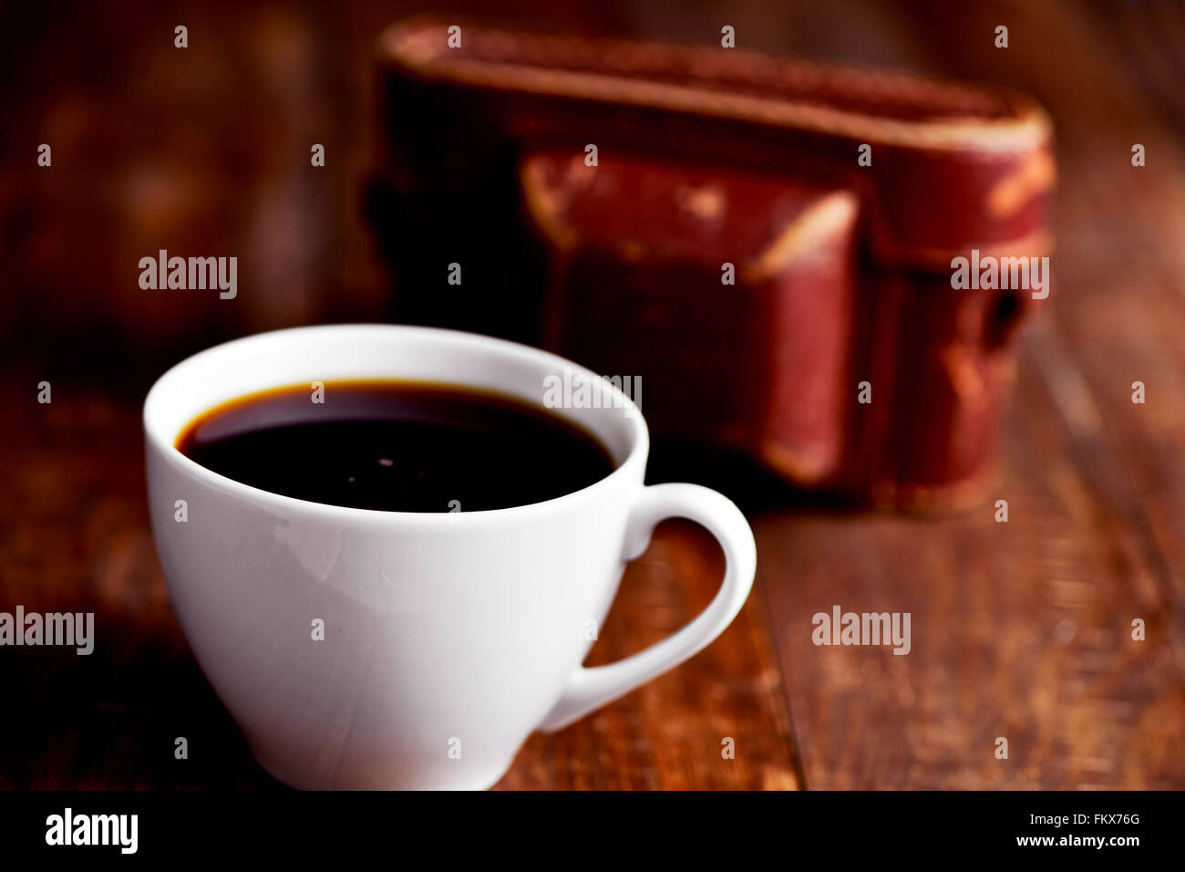 Nahaufnahme von einer Tasse Kaffee und eine alte Kamera in seinem Fall auf einer rustikalen Holzoberfläche Stockfoto