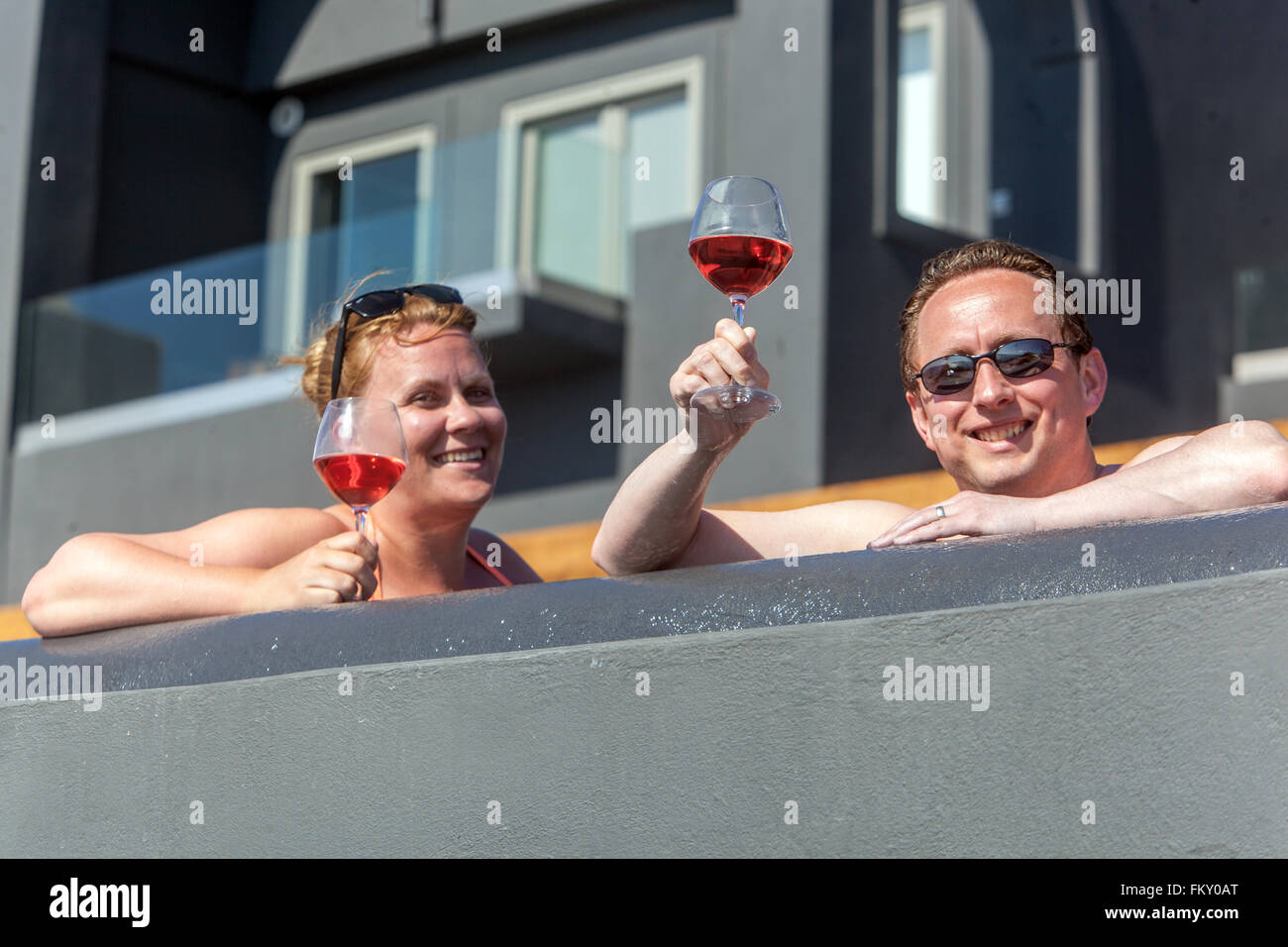 Gäste des Hotels trinken Rotwein auf der Terrasse und sonnen sich ihre Körper, Santorini, Griechenland Touristen genießen den Komfort der Terrassenmenschen auf der Terrasse Stockfoto