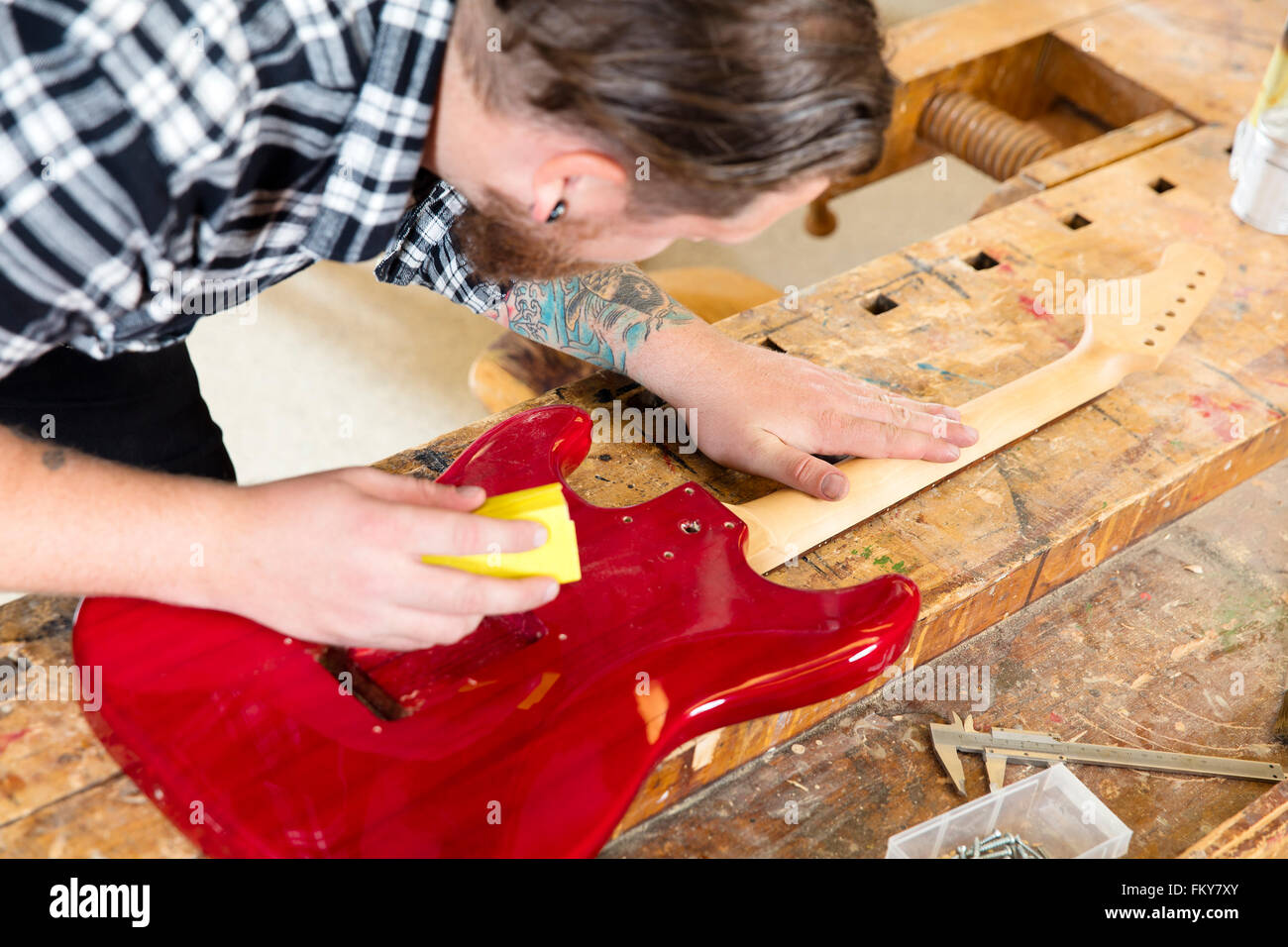 Handwerker, die Schleifen einen Gitarrenhals aus Holz in Werkstatt Stockfoto