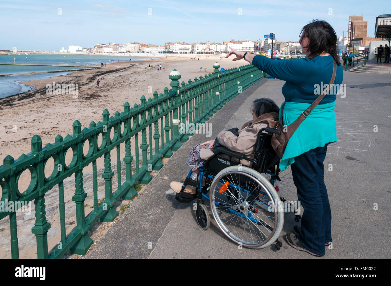 90-Jährige alte Dame und ihre Betreuer oder Helfer am Strand von Margate Promenade. MODEL RELEASED. Stockfoto