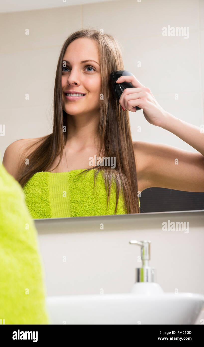 Junge Frau, die ihr Haar kämmen Stockfoto