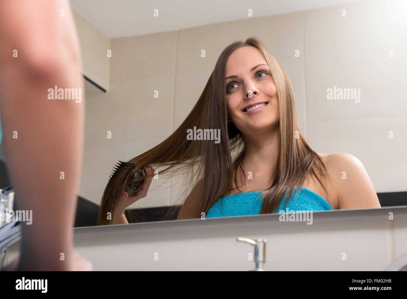Junge Frau, die ihr Haar kämmen Stockfoto
