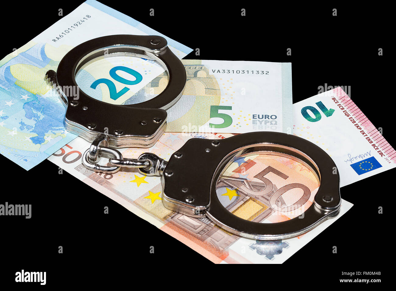 Handschellen und einige Euro-Scheine auf schwarzem Hintergrund Stockfoto
