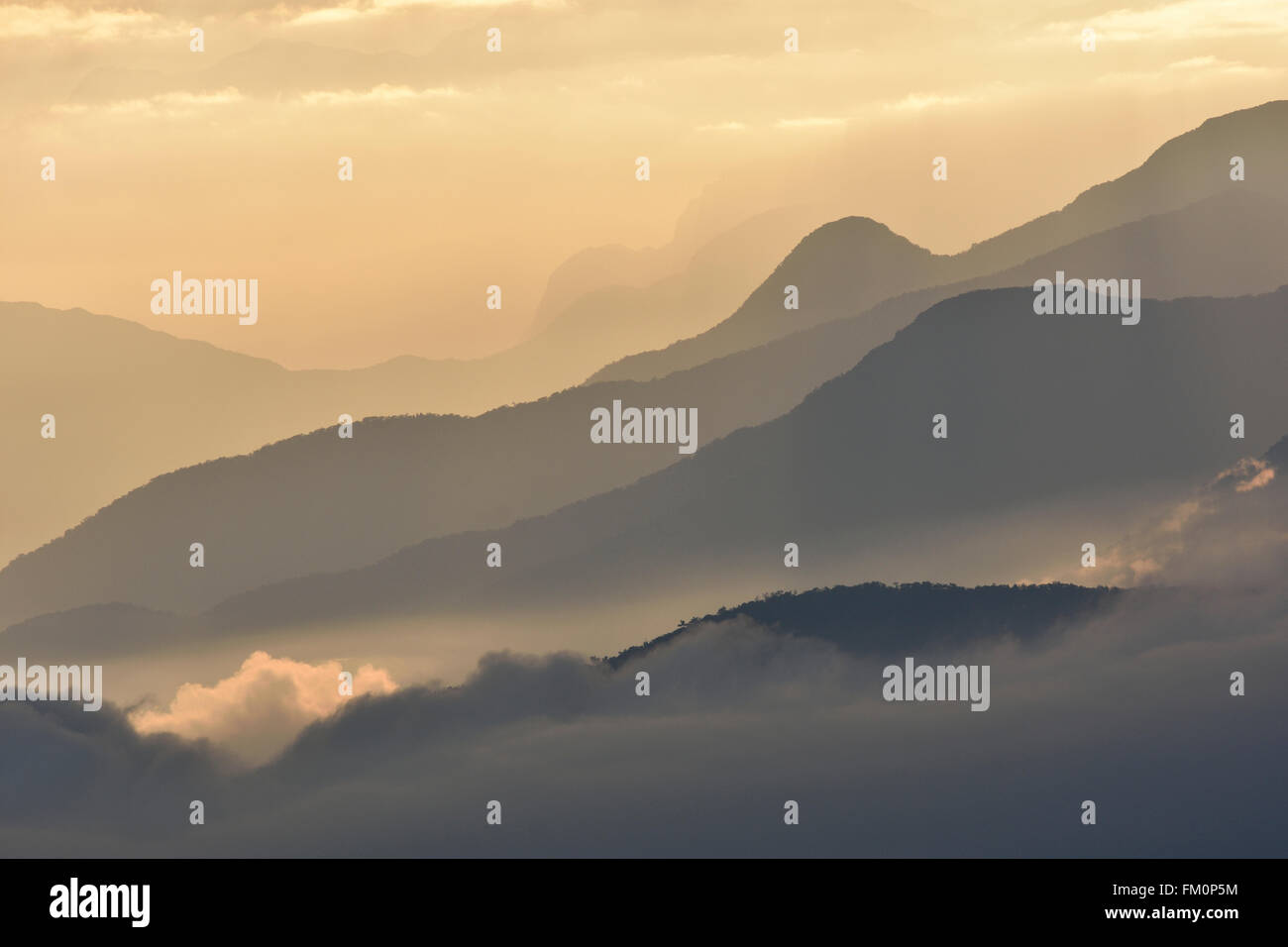 Nebligen Bergrücken in der Morgendämmerung mit flauschigen Wolken eingebettet in die Täler. Stockfoto