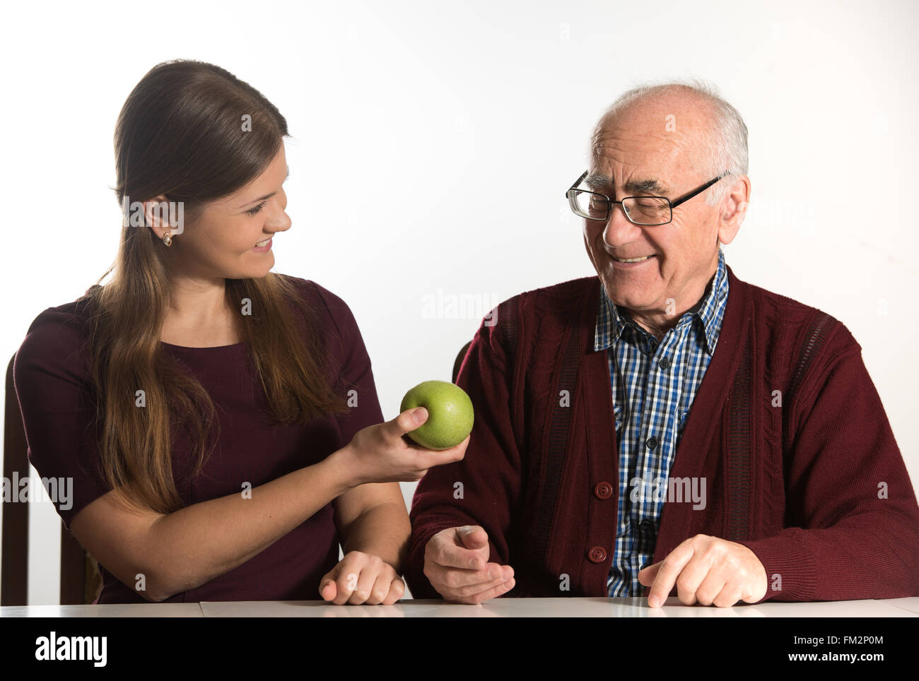 junge Frau hilft senior woman, grünen Apfel zu essen Stockfoto