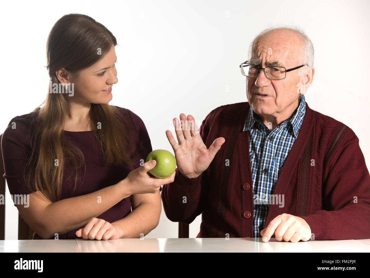 junge Frau hilft senior woman, grünen Apfel zu essen Stockfoto