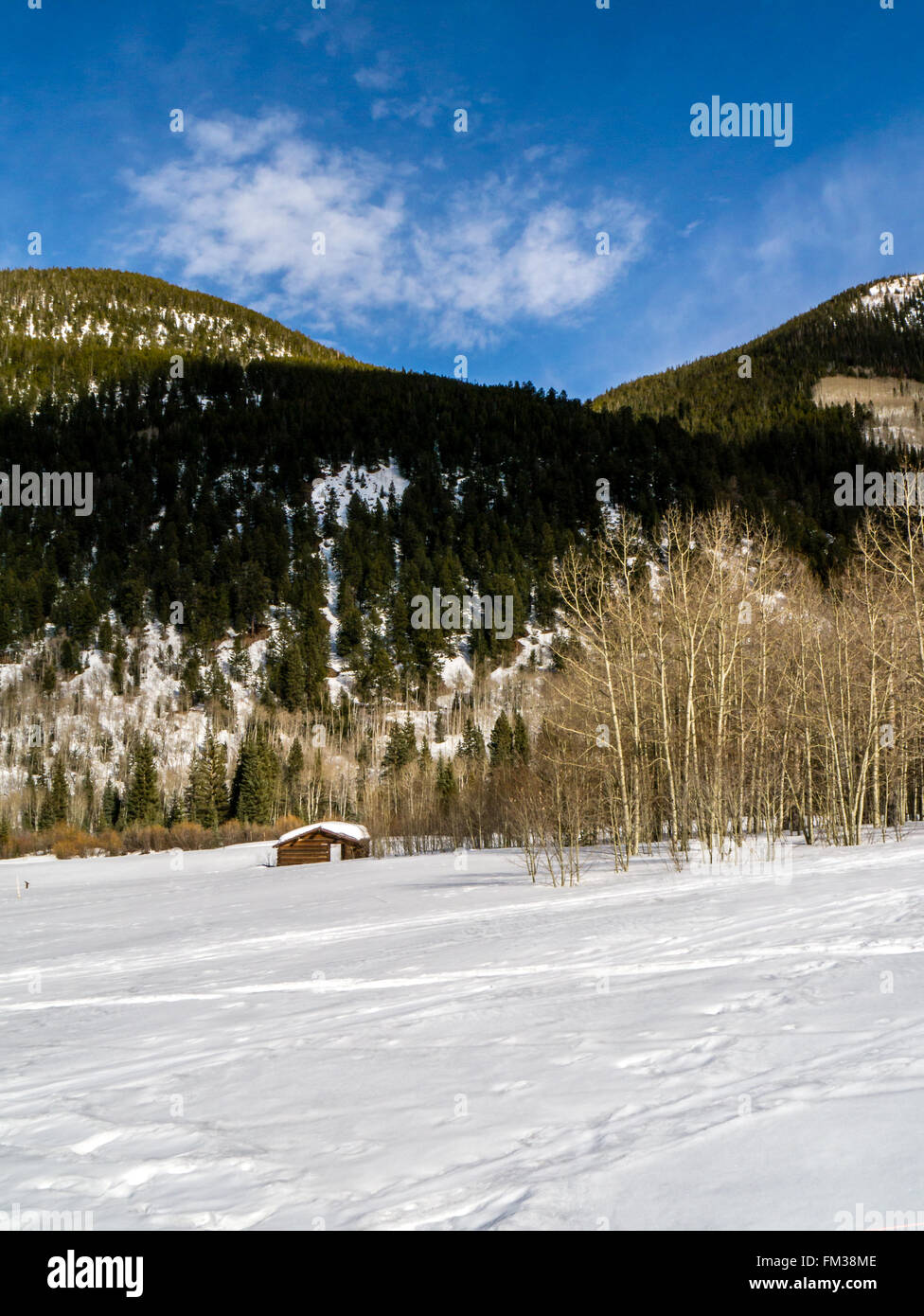 Verwitterte Kabine allein in den verschneiten Bergen unter blauem Himmel Stockfoto