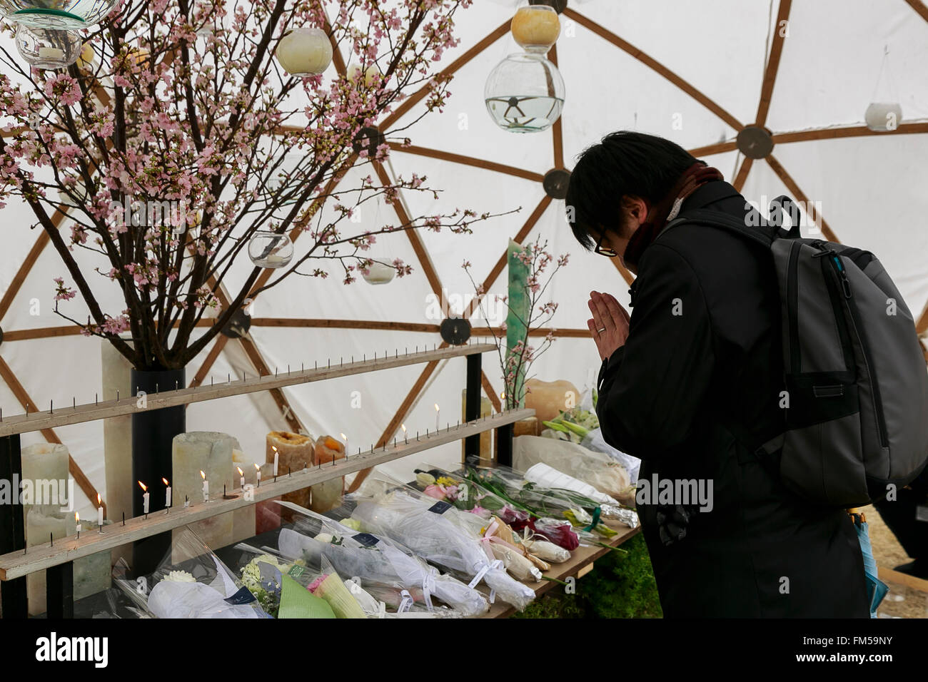 Tokio, Japan. 11. März 2016. Tokio, Japan. 11. März 2016. Ein Mann betet anlässlich des fünften Jahrestages der Great East Japan Erdbeben und Tsunami-Katastrophe in den Frieden auf Erden Gedenkfeier im Hibiya-Park am 11. März 2016, Tokio, Japan. Fast 19.000 Menschen starben durch das Erdbeben der Stärke 9,0 und der nachfolgende Tsunami, die Nordostküste Japans vor 5 Jahren getroffen. Fünf Jahre nach dem Ereignis sind einige 174.000 Überlebende noch in Notunterkünften. © Aflo Co. Ltd./Alamy Live-Nachrichten Stockfoto
