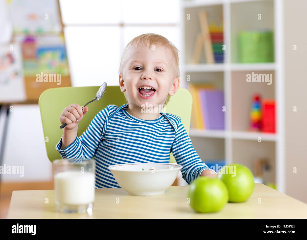 niedlichen kleinen Jungen essen Müsli mit Milch im Kindergarten Stockfoto
