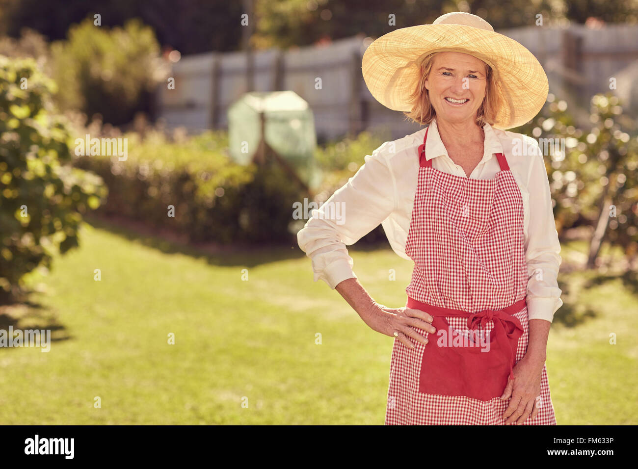 Lächelnde ältere Frau in ihrem Garten an einem Sommertag Stockfoto
