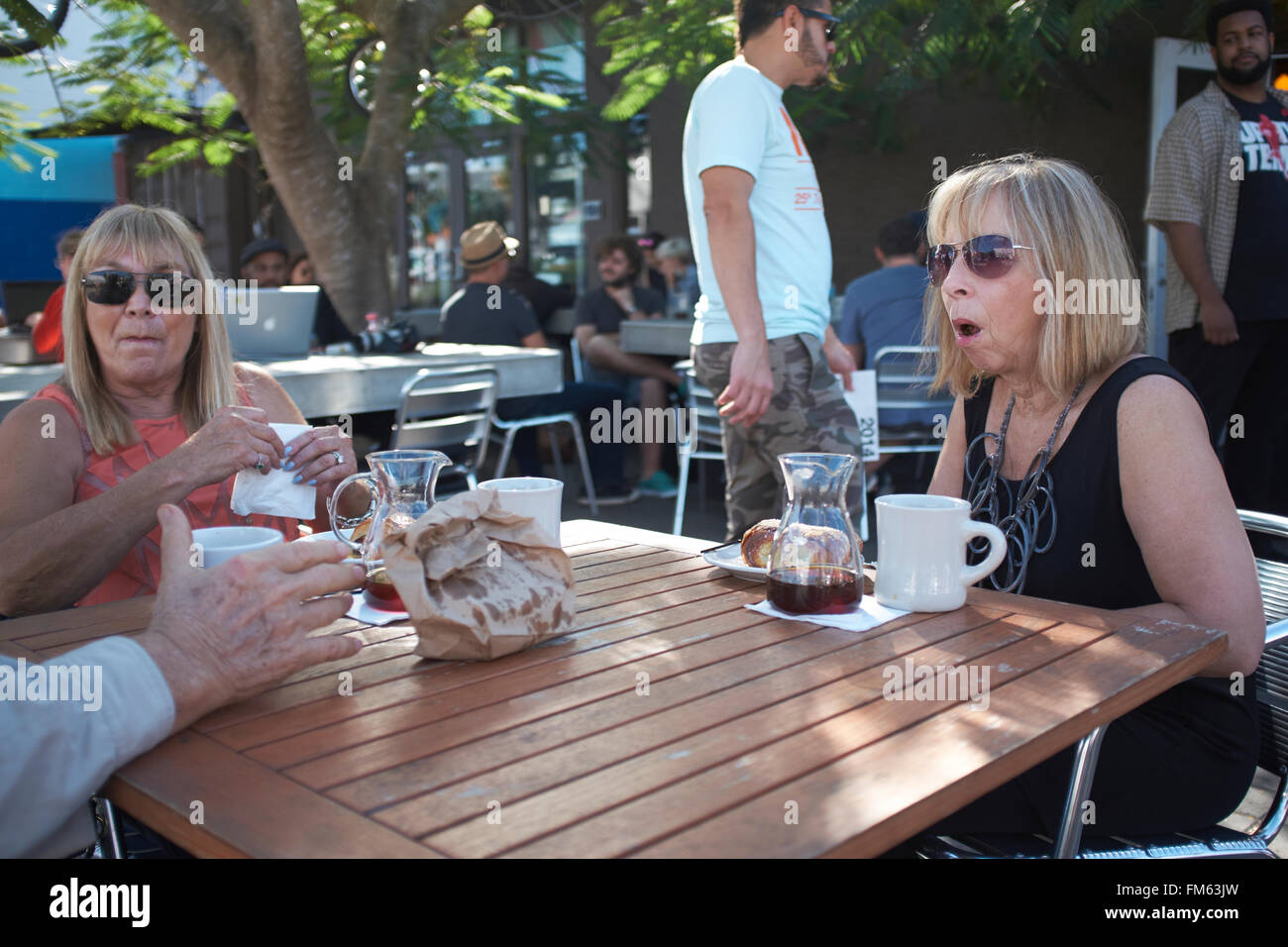 Zwei Frauen sitzen im Café und im Gespräch mit einem Mann Stockfoto