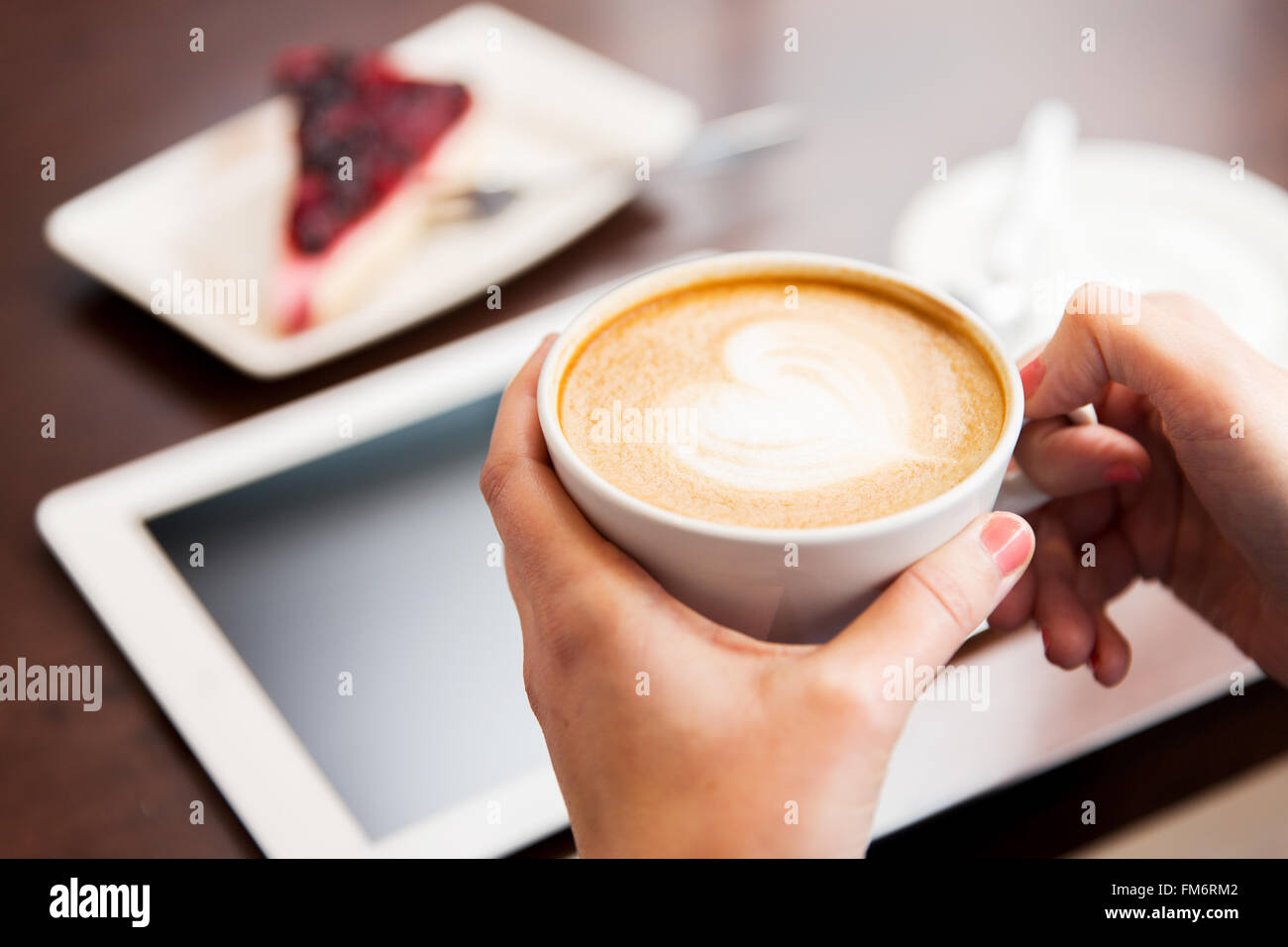 Nahaufnahme von Händen mit Tablet-pc, Kaffee und Kuchen Stockfoto