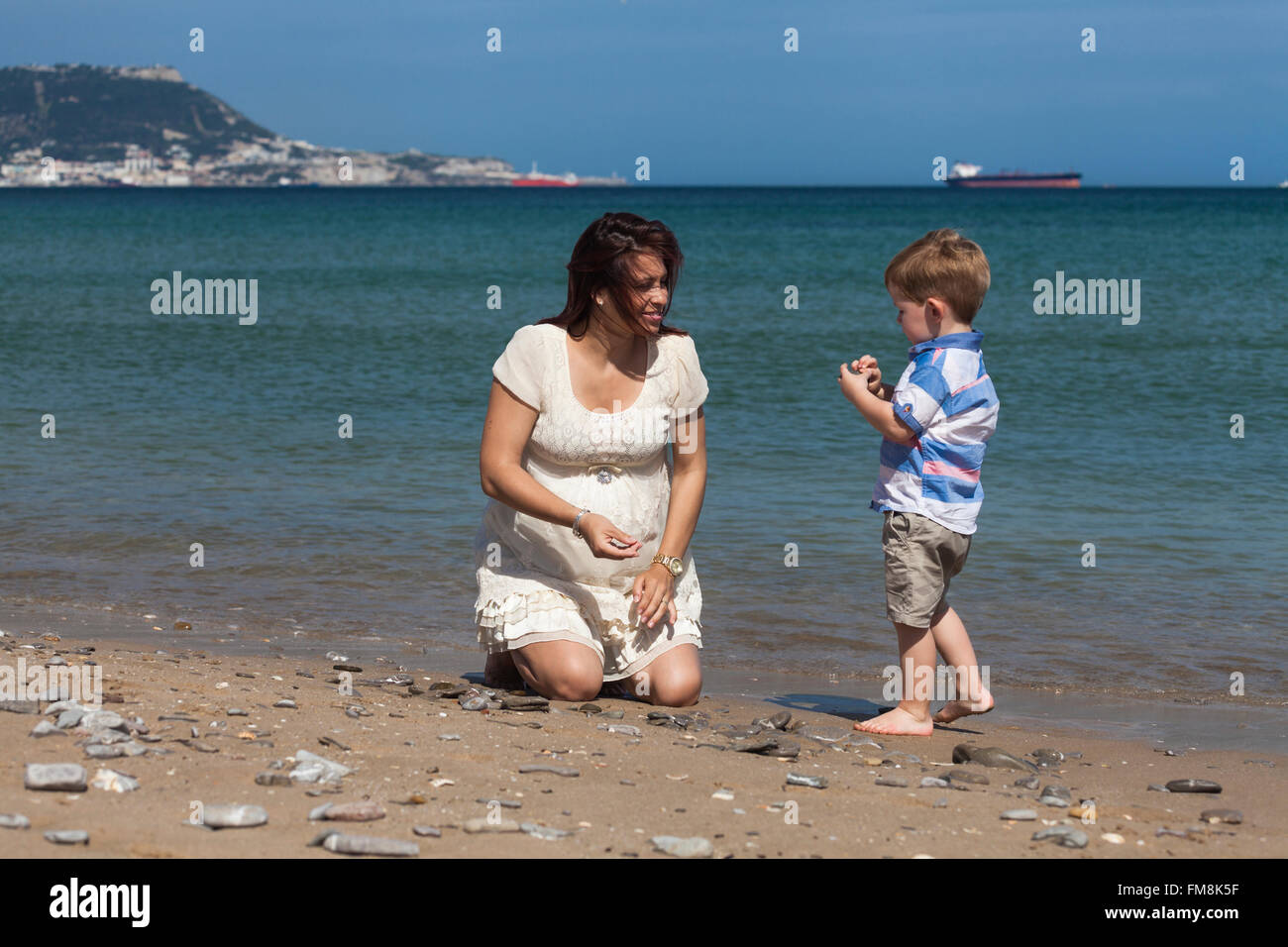 Glücklich schwanger Frau mit Kind Jungen spielen und genießen sonnigen Tag am Strand in Spanien. Stockfoto