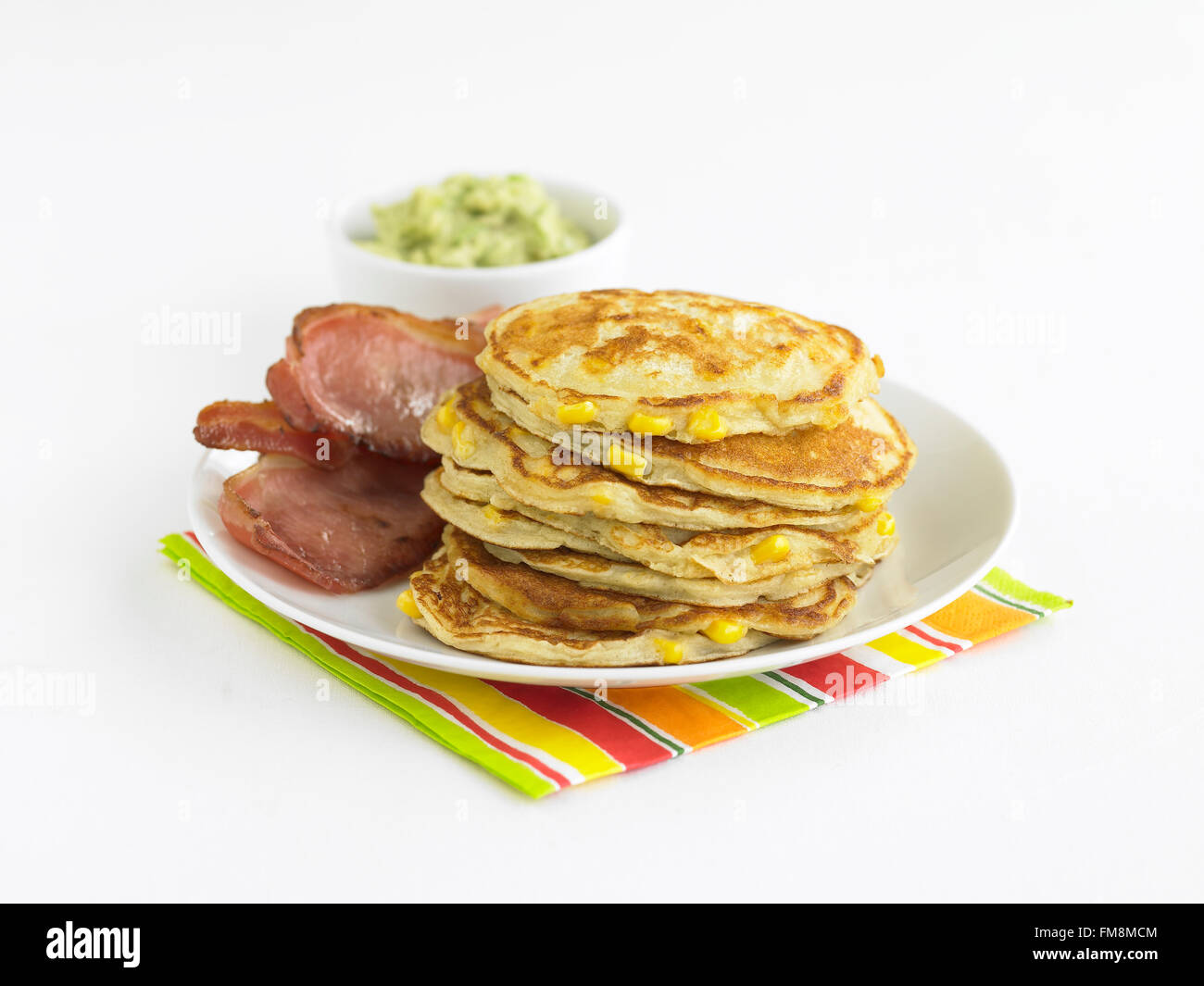 Stapel von Pfannkuchen und Speck Speckscheiben auf Teller, Schüssel mit Guacamole im Hintergrund Stockfoto