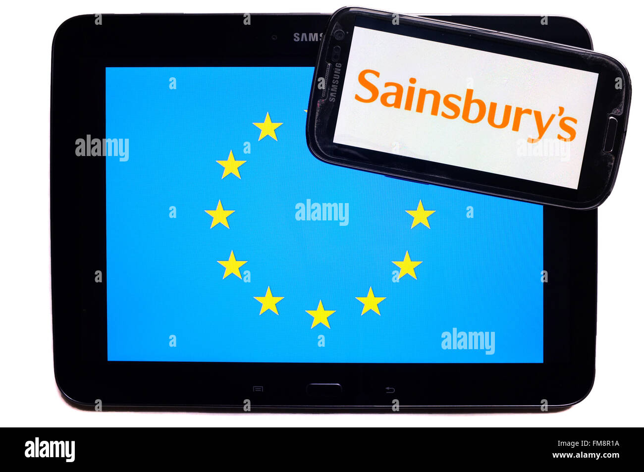 Ein Smartphone mit dem Sainsbury Logo drauf auf einem Tablet mit der EU-Flagge auf weißem Hintergrund fotografiert. Stockfoto