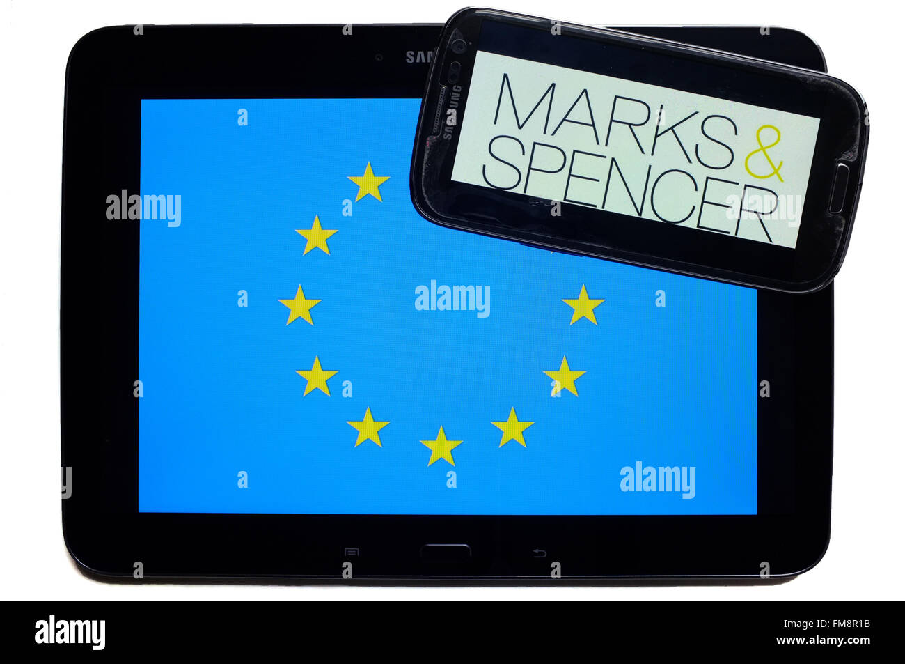 Ein Smartphone mit dem Marks & Spencer Logo durch eine Tablette mit der EU-Flagge auf weißem Hintergrund fotografiert. Stockfoto