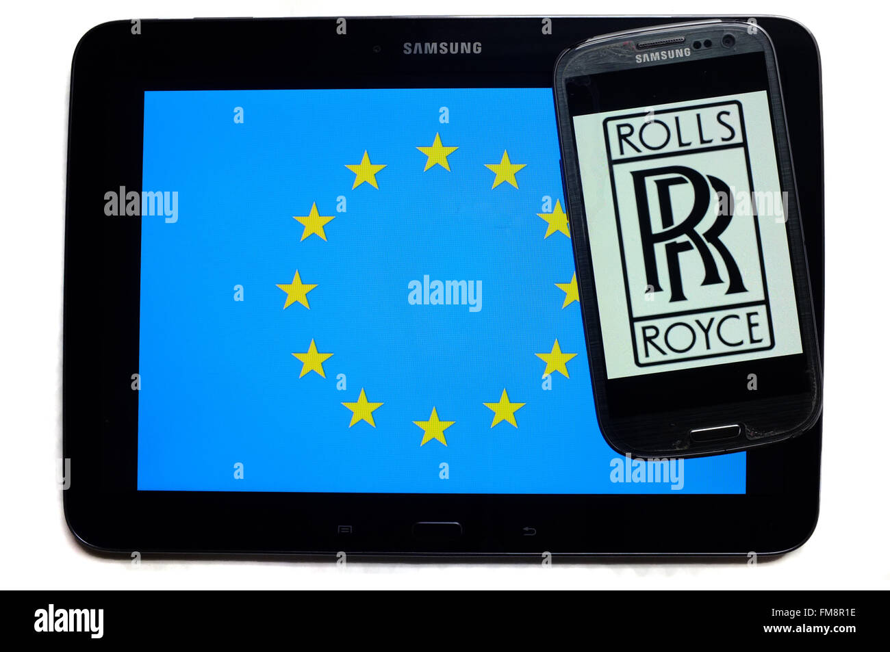 Ein Smartphone mit dem Rolls-Royce-Logo drauf auf einem Tablet mit der EU-Flagge auf weißem Hintergrund fotografiert. Stockfoto