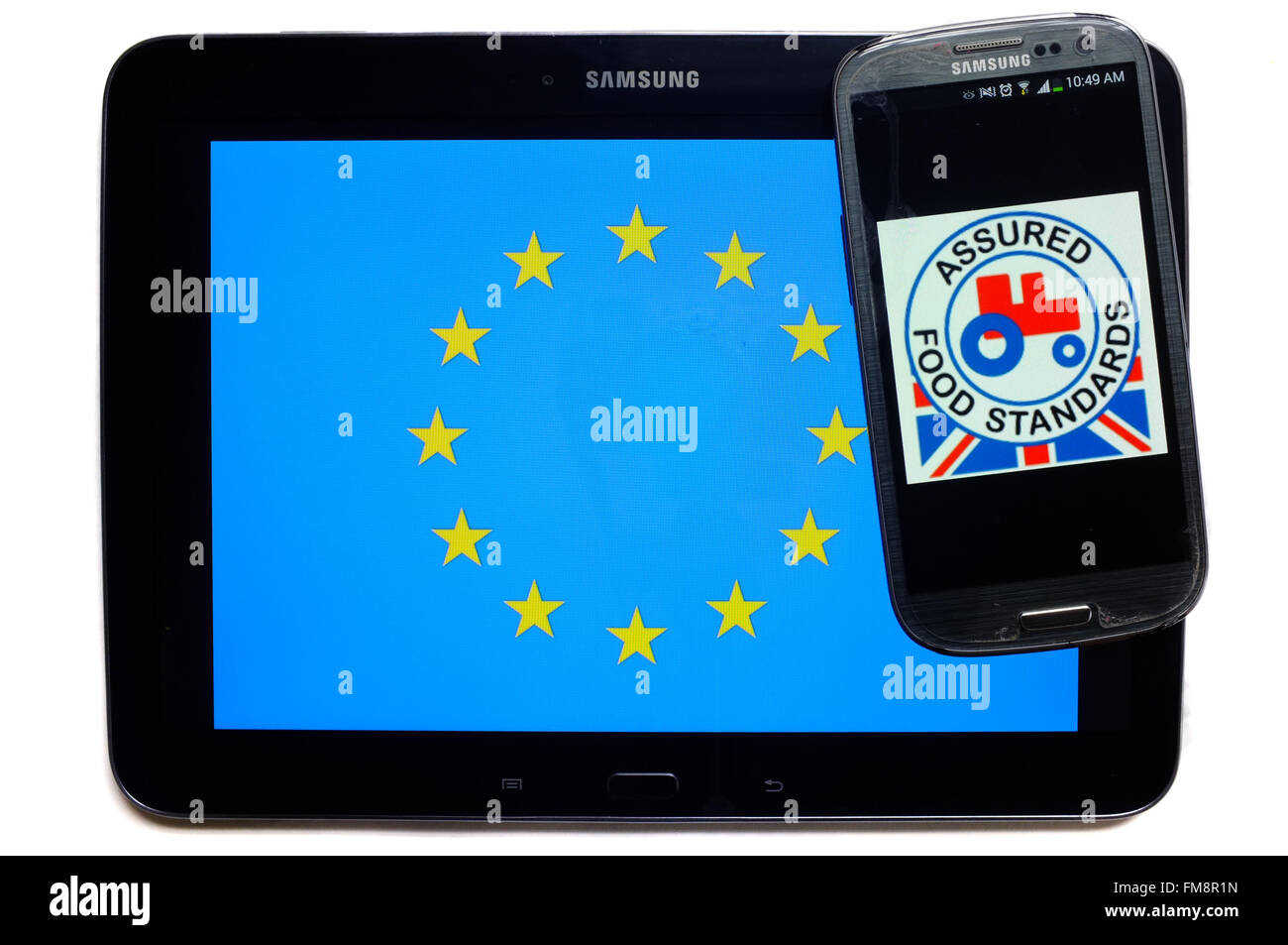 Ein Smartphone mit der garantierten Food Standards-Logo drauf auf einem Tablet mit der EU-Flagge auf weißem Hintergrund. Stockfoto