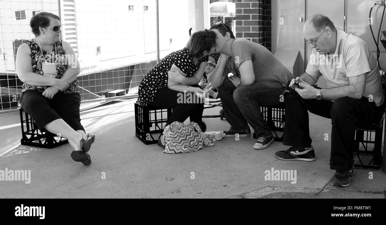 Paar küssen, während Mutter und Baby sitzend auf Milchkisten bei Ekka landwirtschaftlichen Showground, Brisbane, Australien schauen auf Stockfoto