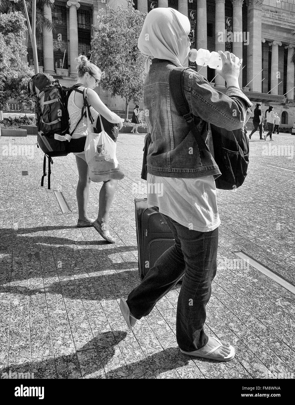 Rucksacktouristen, die kämpfen, tragen Ihr Gepäck tragen Hijab und trinken Wasser im King George Square, Brisbane, Queensland, Australien Stockfoto