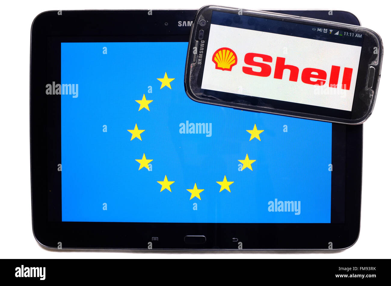 Ein Smartphone mit dem Shell-Logo drauf auf einem Tablet mit der EU-Flagge auf weißem Hintergrund fotografiert. Stockfoto
