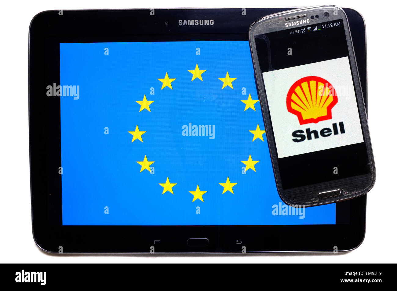 Ein Smartphone mit dem Shell-Logo drauf auf einem Tablet mit der EU-Flagge auf weißem Hintergrund fotografiert. Stockfoto