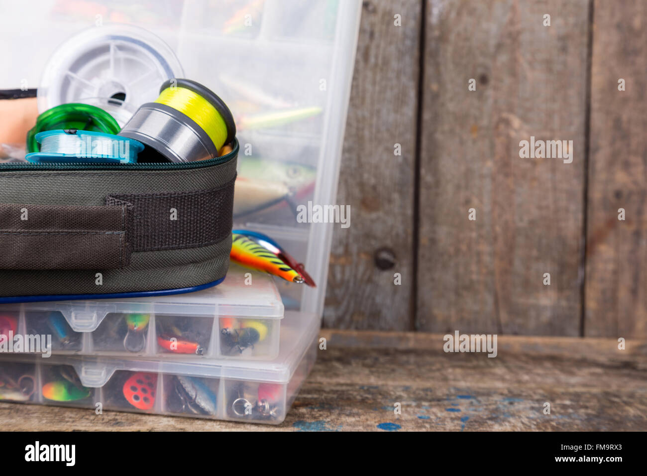 Angelgeräte, Köder und Köder in den Kästen auf Holzbalken Hintergrund für Outdoor-aktive Unternehmen Stockfoto