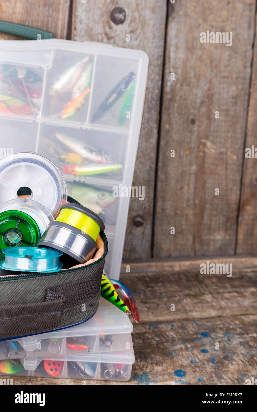 Angelgeräte, Köder und Köder in den Kästen auf Holzbalken Hintergrund für Outdoor-aktive Unternehmen Stockfoto