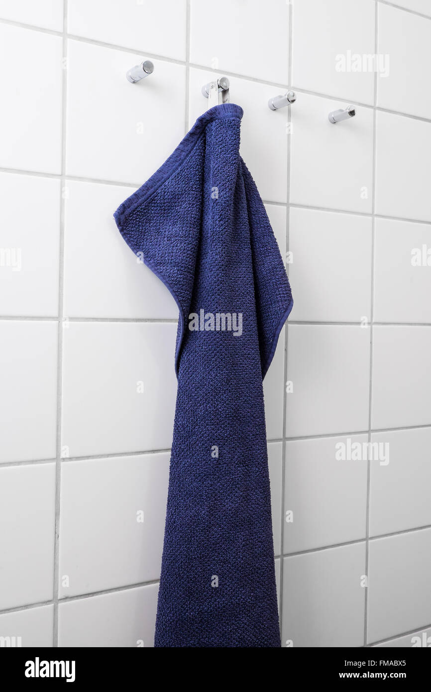 Blaues Handtuch an weißen Fliesen Wand hängen Stockfoto