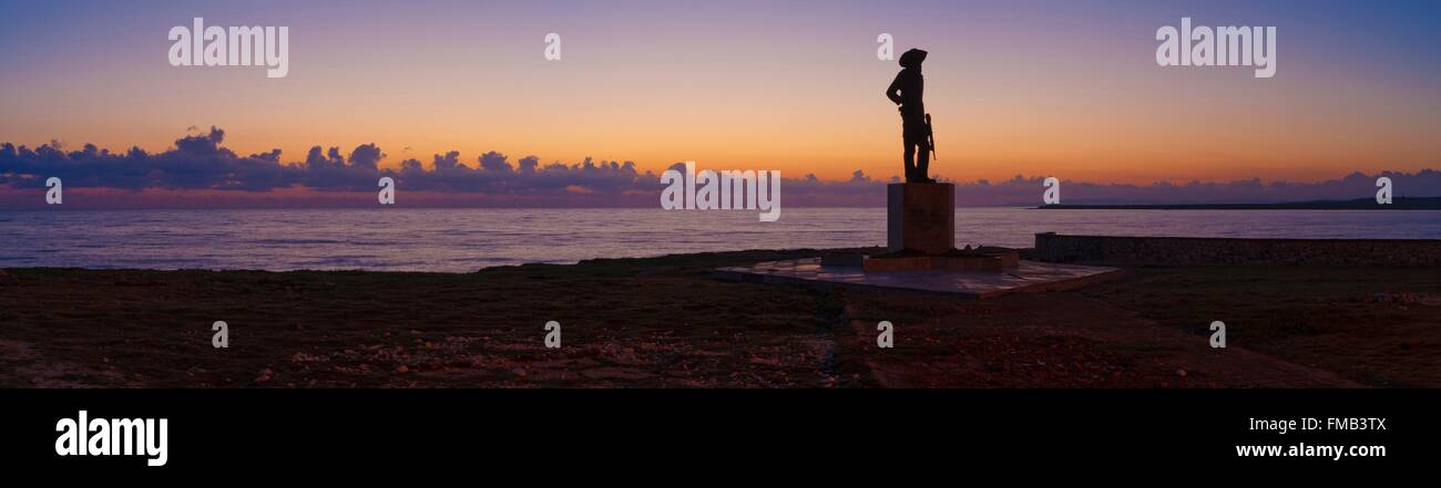 Cuba, Holguin, Gibara, Panorama am Strand bei Sonnenuntergang mit Silhouette einer Statue zu Ehren der revolution Stockfoto