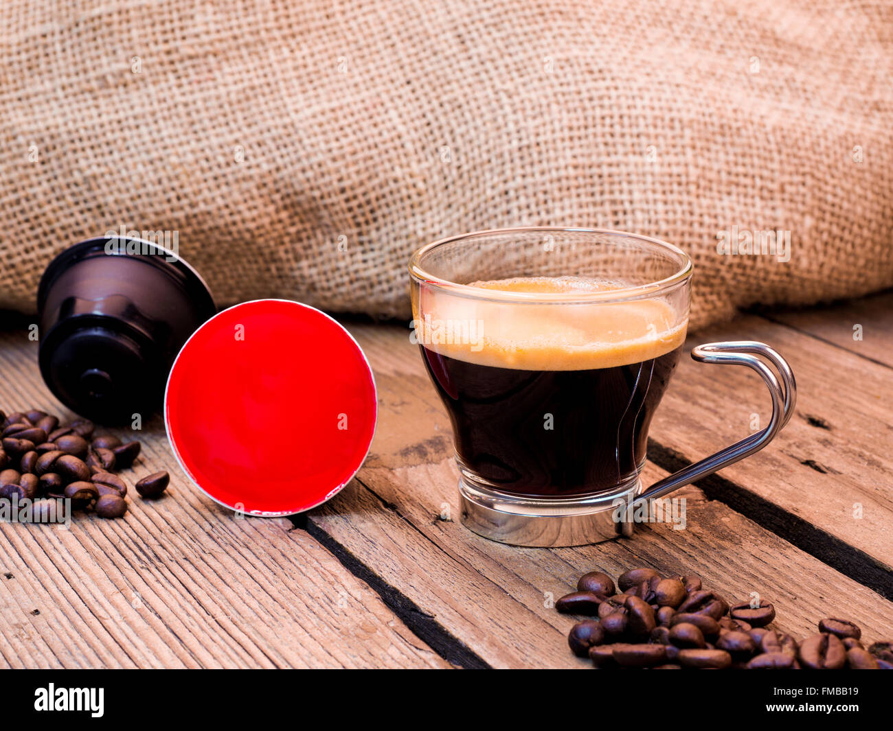 Tasse Kaffee und Hülsen auf Holztisch Stockfoto