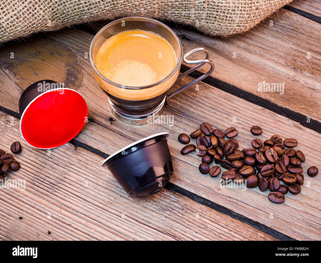 Tasse Kaffee und Hülsen auf Holztisch Stockfoto