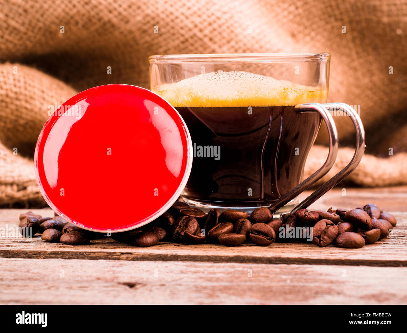 Tasse Kaffee und Hülsen auf Holztisch Stockfoto