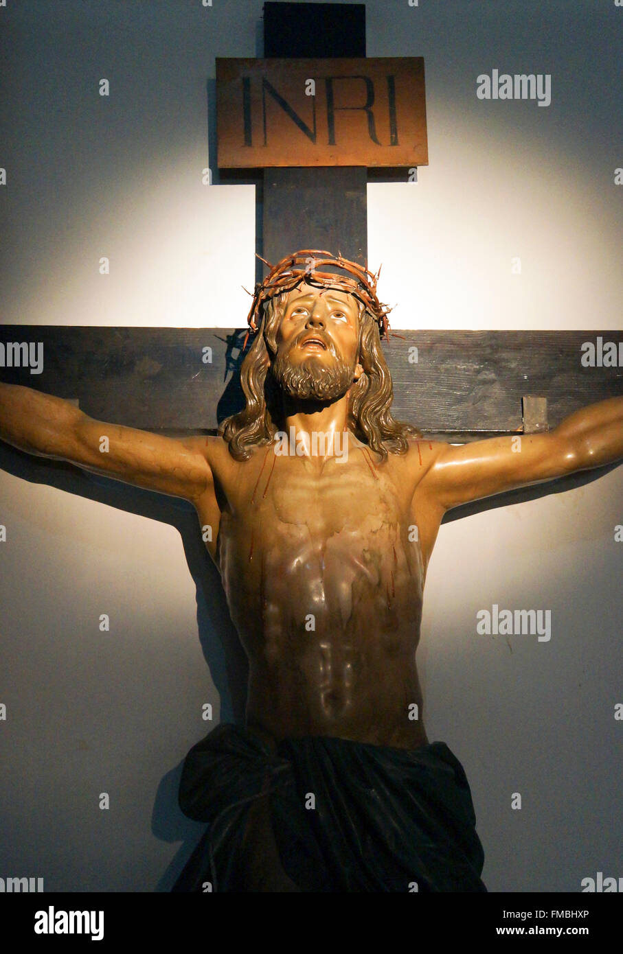 Statue von Jesus am Kreuz hängend, mit Licht auf seinem Gesicht Stockfoto