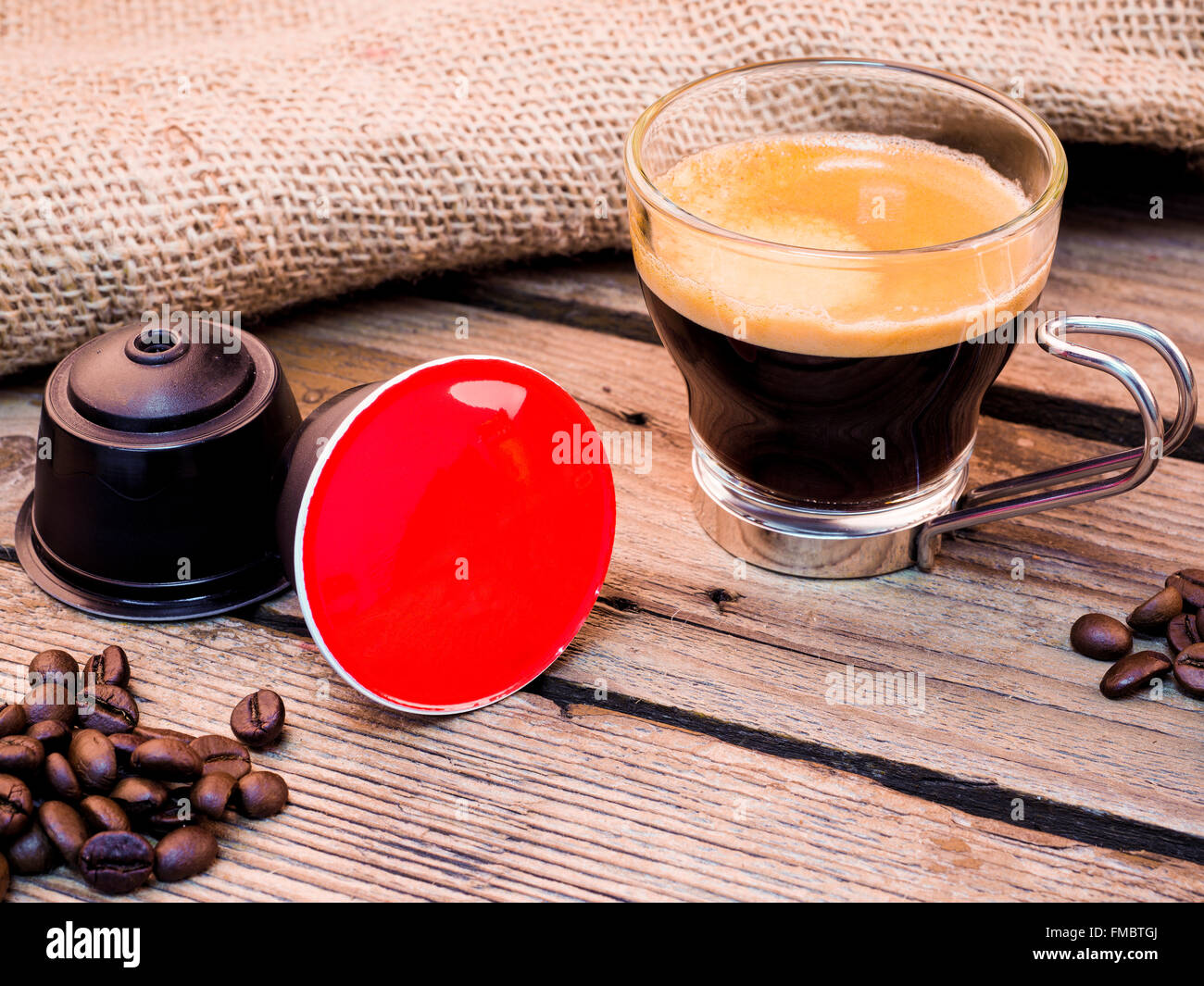 Tasse Kaffee und Hülsen auf Holztisch Stockfoto
