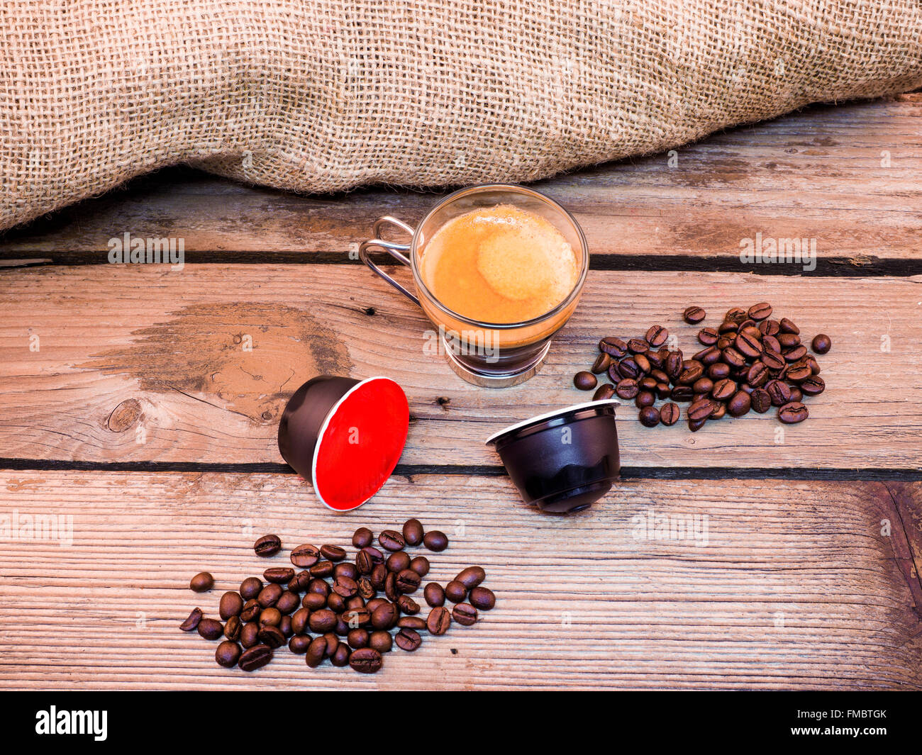 Tasse Kaffee und Hülsen auf Holztisch Stockfoto
