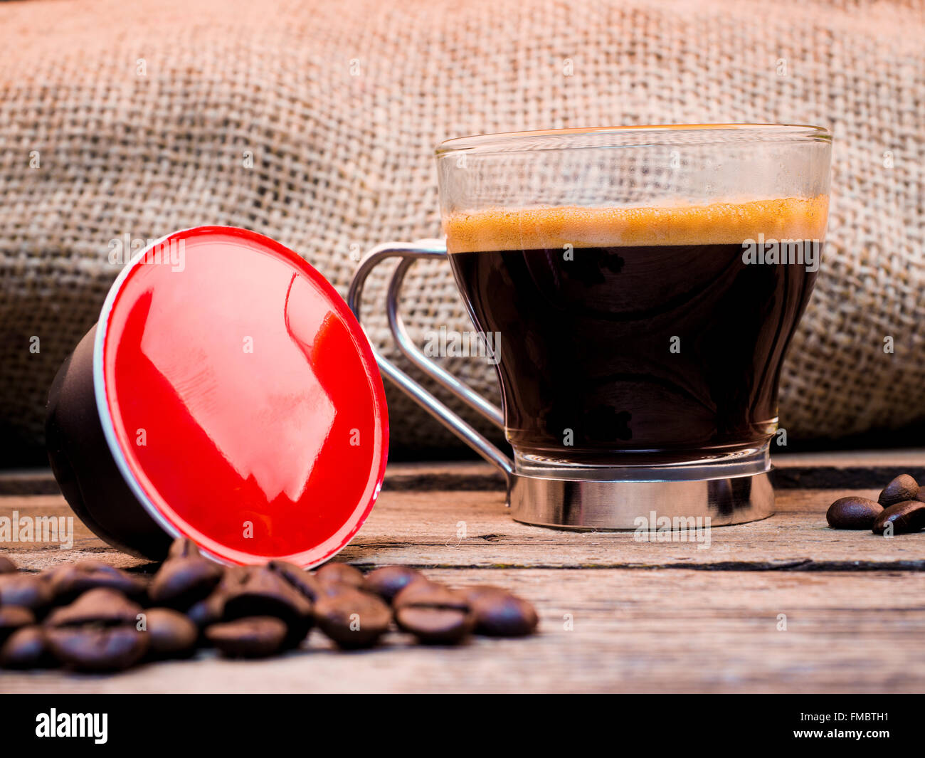 Tasse Kaffee und Hülsen auf Holztisch Stockfoto